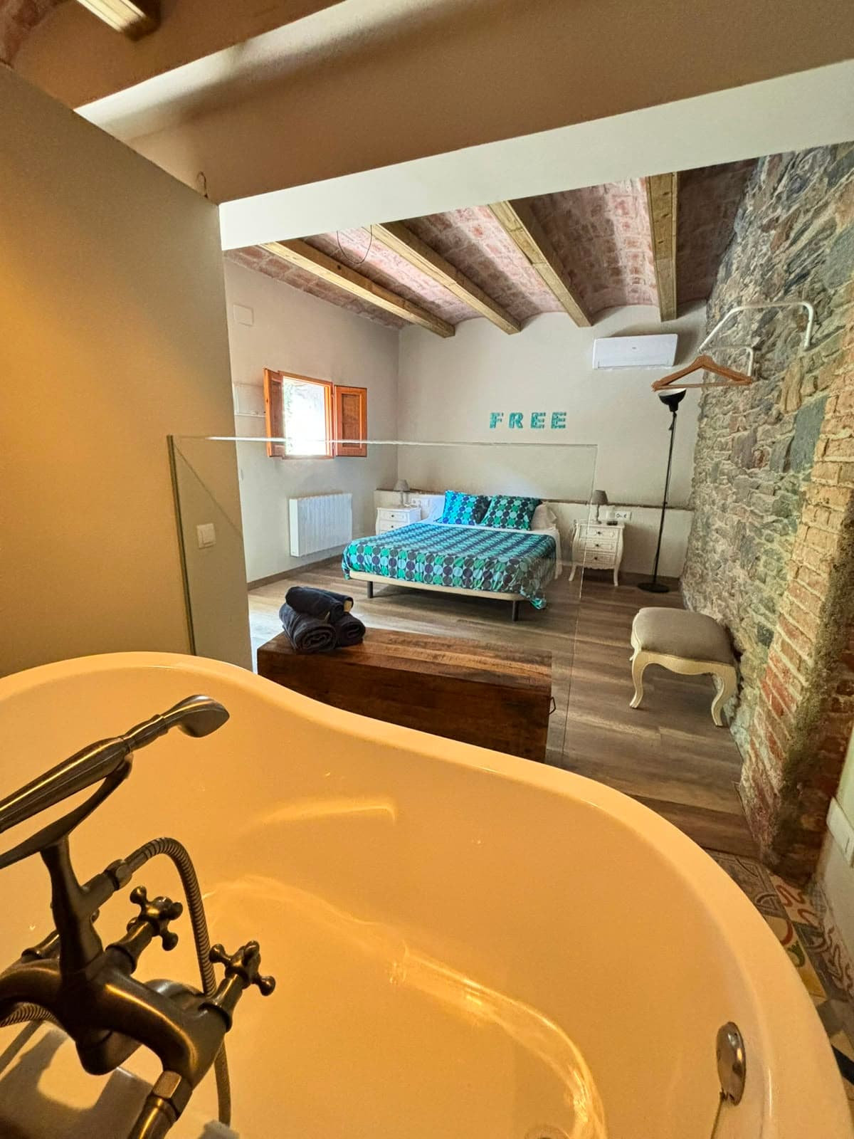 Banyera en primer terme amb vistes al llit i les lletres FREE al fons de l'habitació