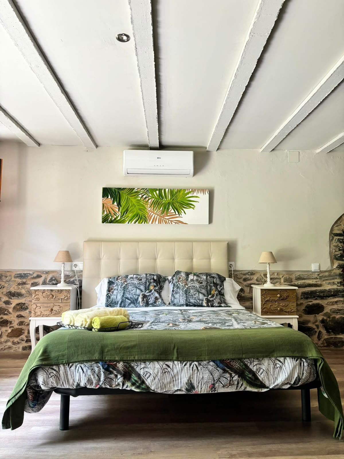 Llit de matrimoni amb capçal tapissat i estampat tropical de micos